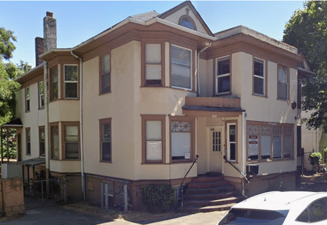 A two story house with a white car parked in front.